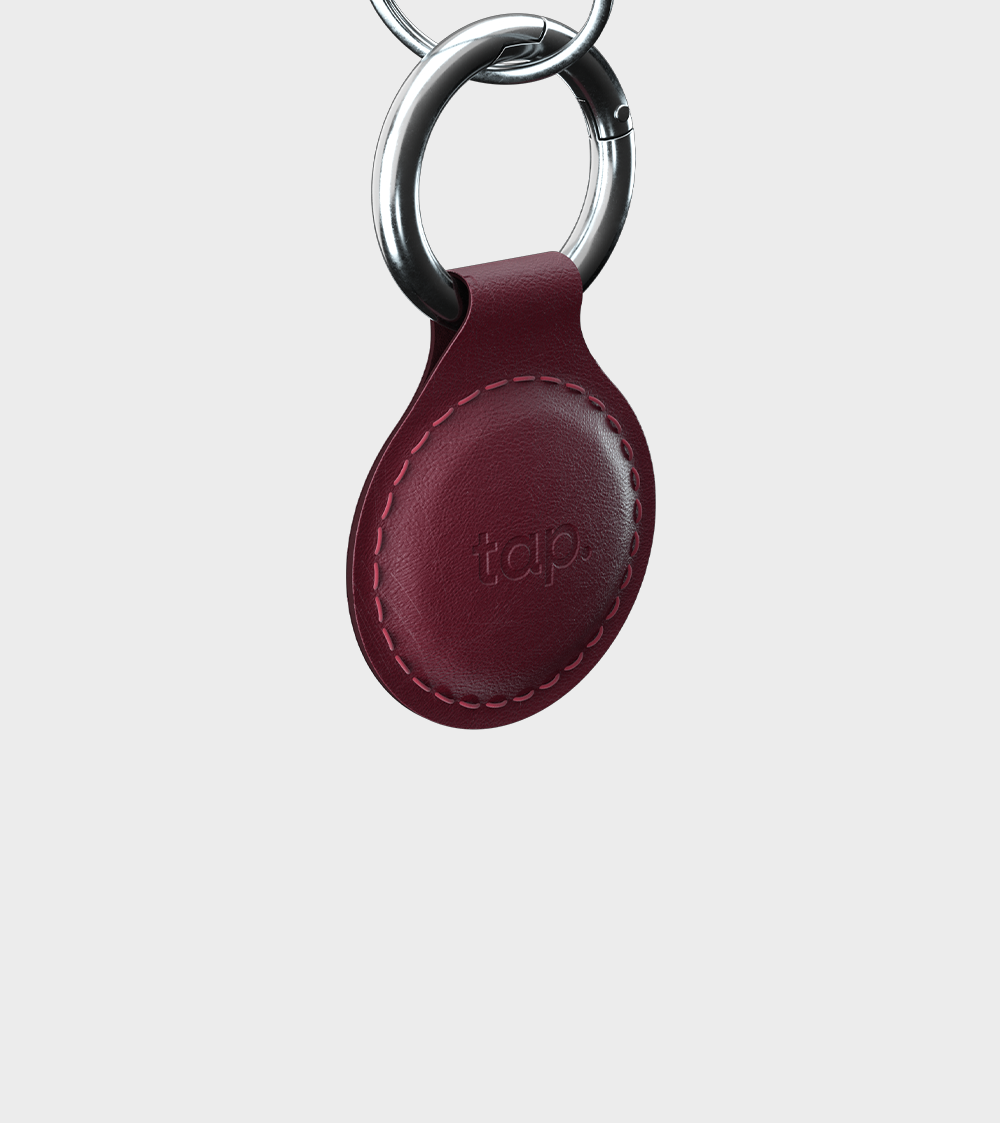Close-up of red leather keychain with metal ring and branding