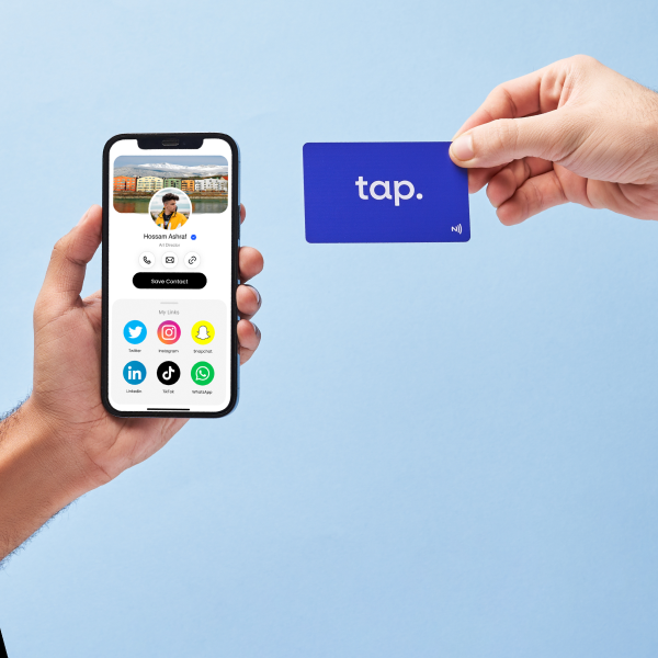 Hands holding smartphone with contact info and NFC card demonstrating tap technology on blue background.