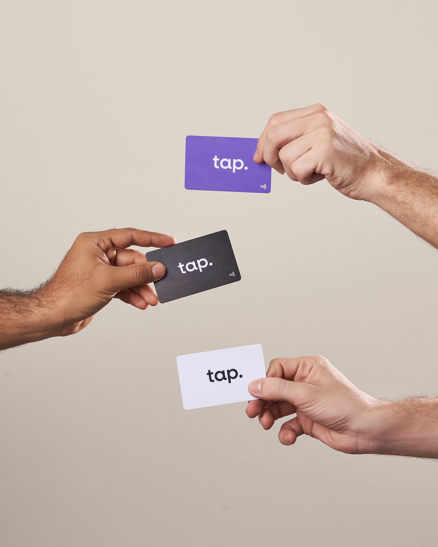 Three hands exchanging colorful tap NFC cards on a neutral background.