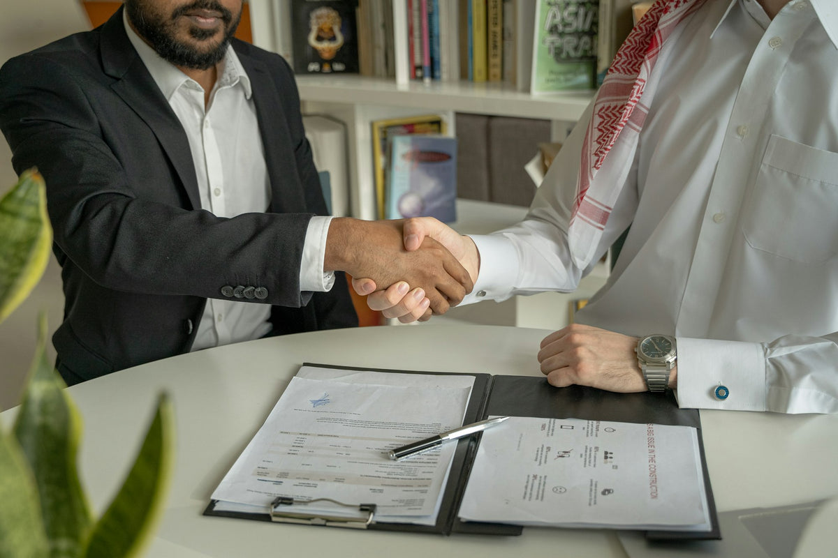 Two professionals shaking hands across a meeting table
