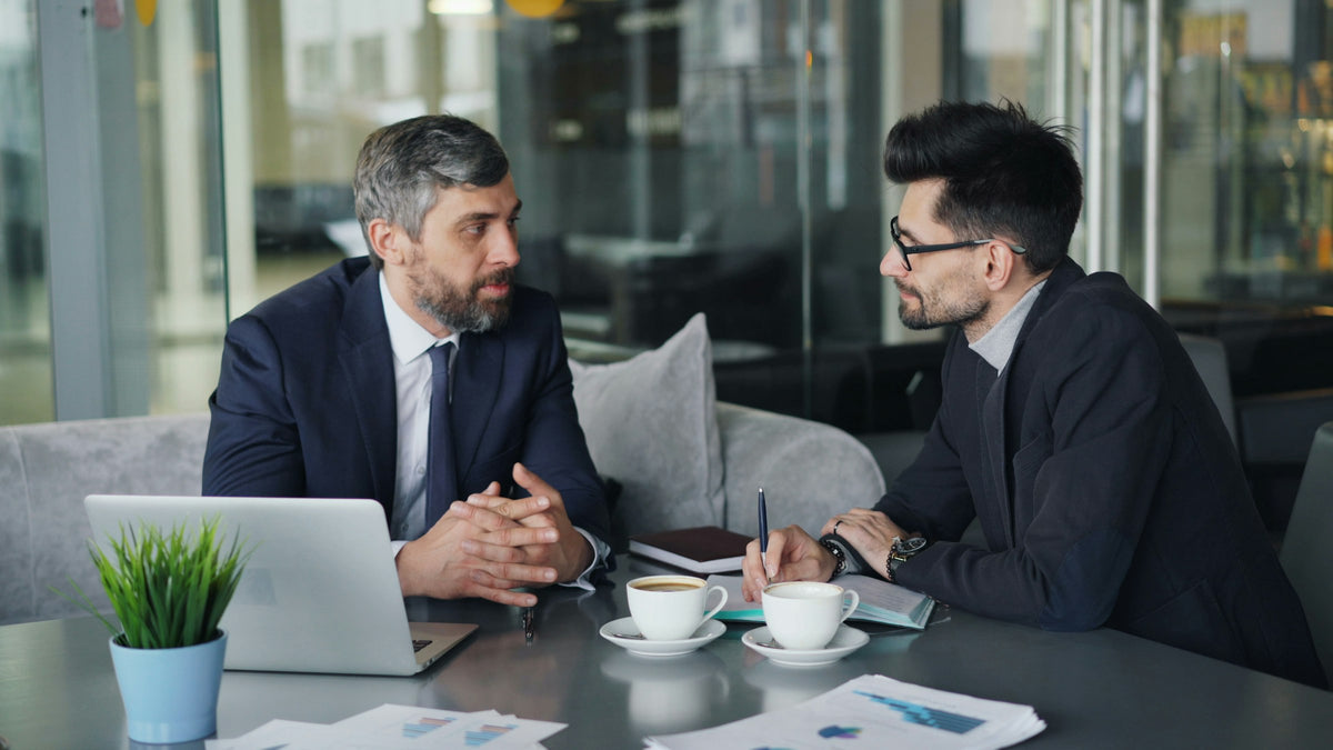 Two colleagues meet over coffee and a laptop