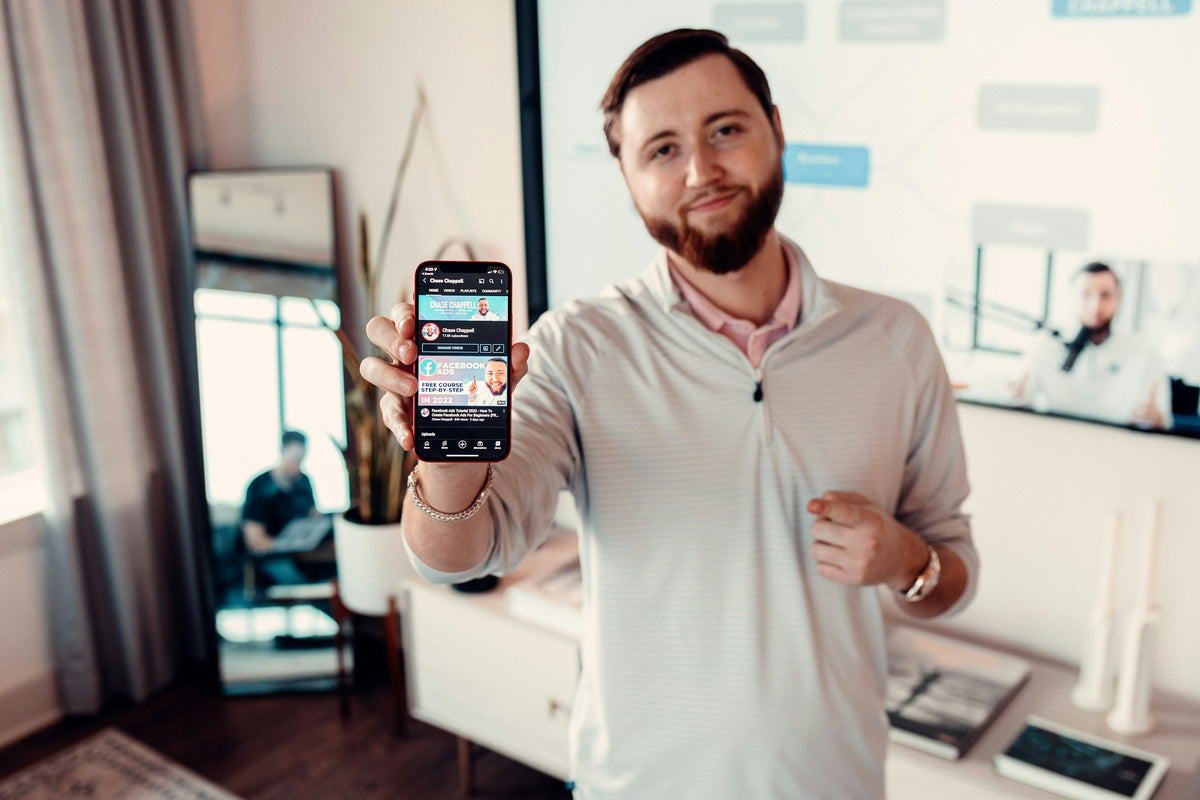 A man holds up his phone to show his profile
