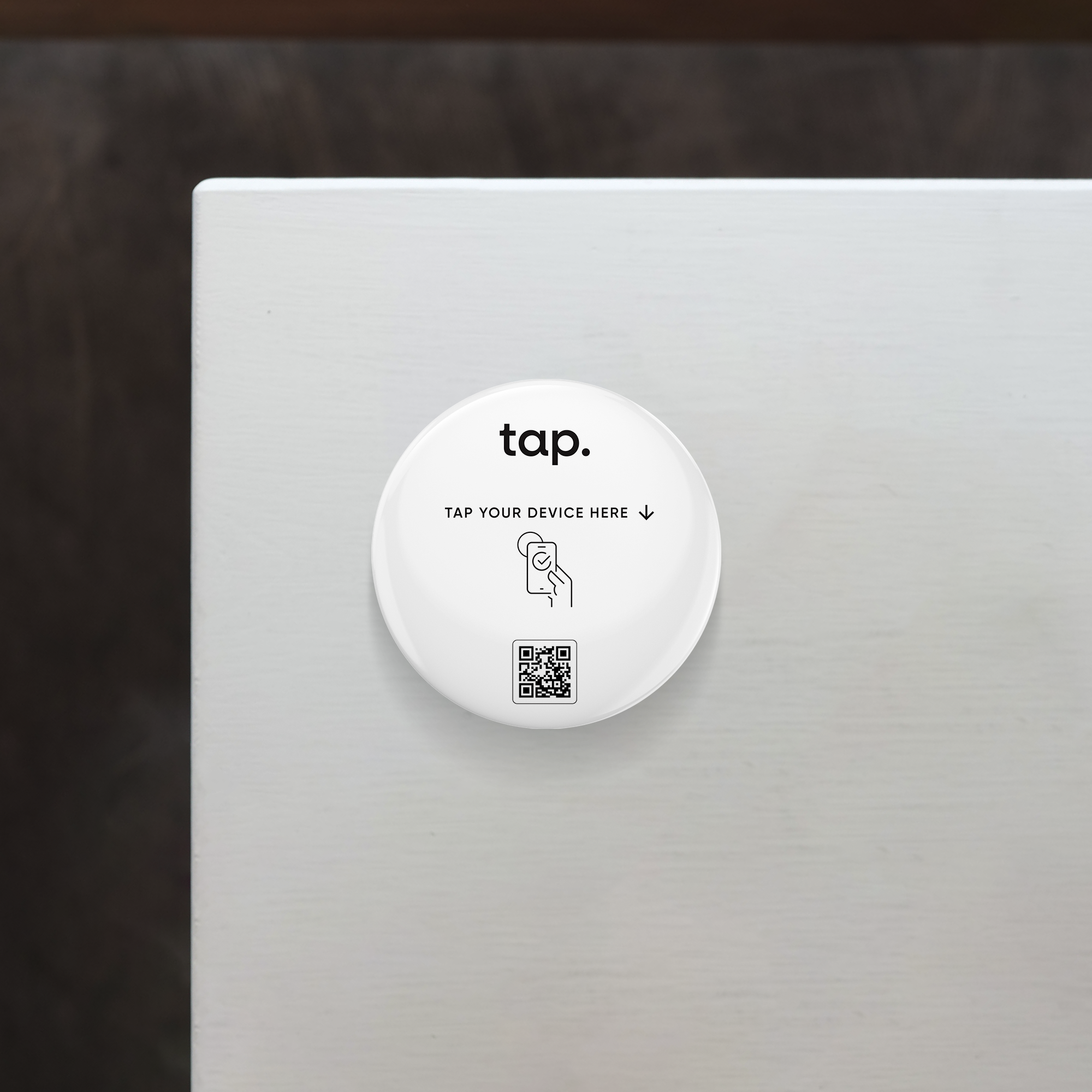 NFC tap point device with QR code for smartphone interaction on a white table surface.